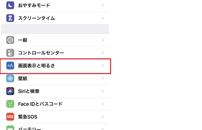 iPhoneのホーム画面で、ネジマークの設定アイコンをタップすると、メニュー一覧が表示されます。画面の中段くらいに画面表示と明るさという項目がありますので選択します。